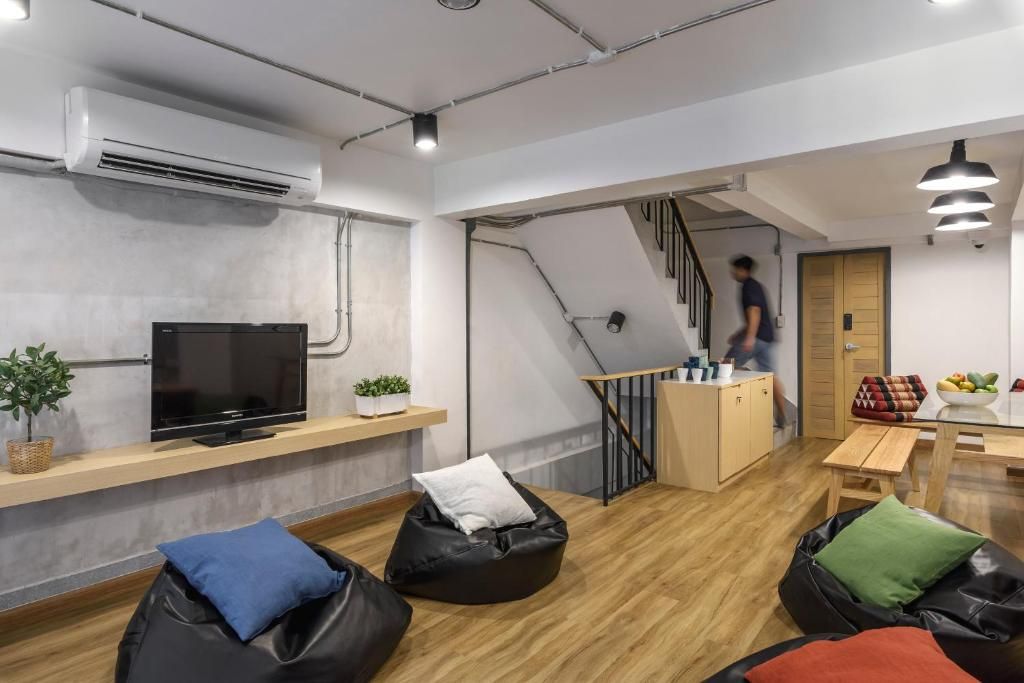 Un espacio moderno para vivir con televisión de pantalla plana, pufs, una escalera y una pequeña cocina.