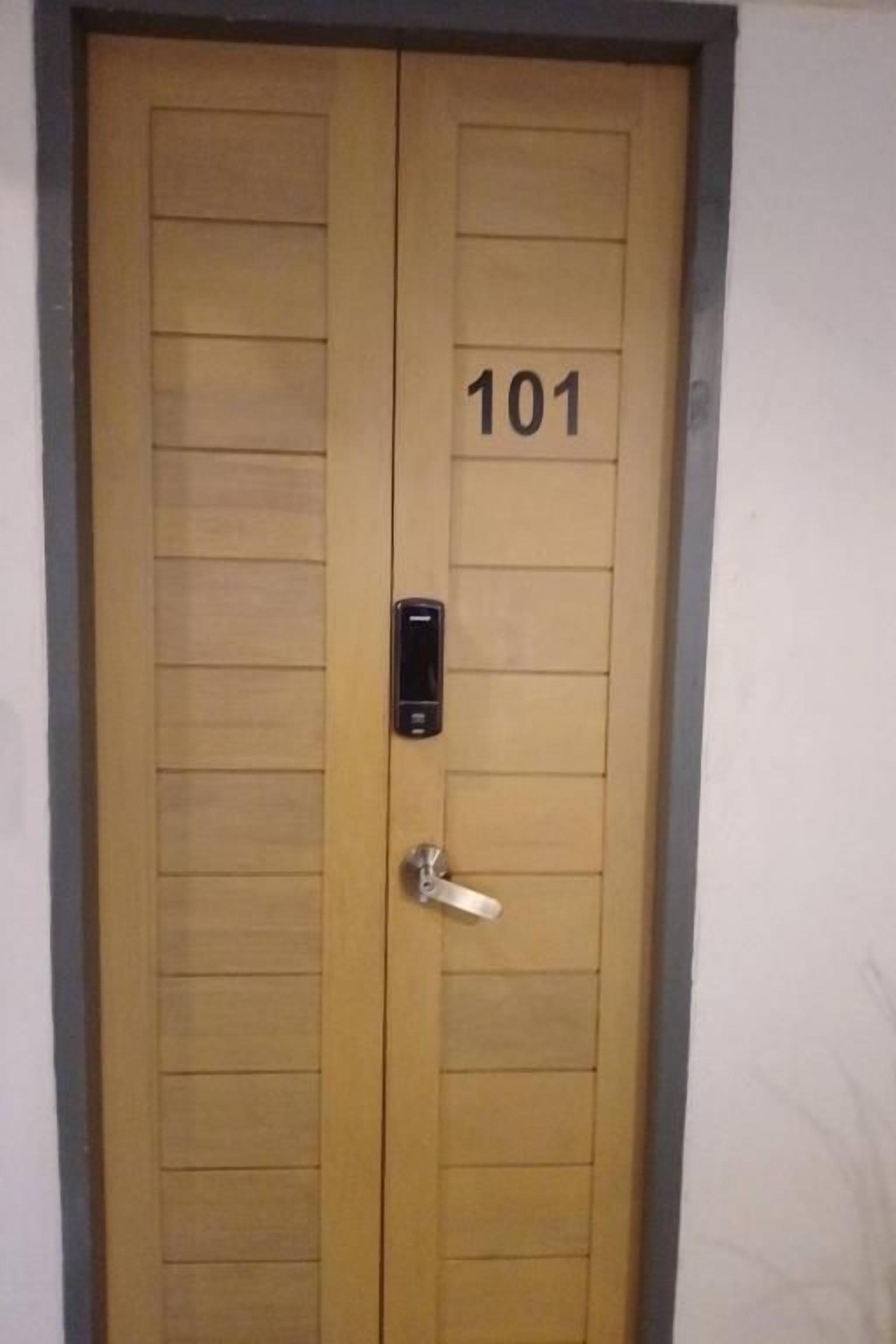 Una puerta doble de madera con el número 101, una mirilla y un pequeño cierre electrónico.