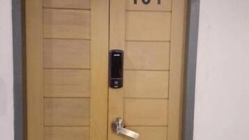 Una puerta doble de madera con el número 101, una mirilla y un pequeño cierre electrónico.