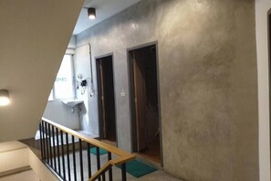 Una escalera conduce a un baño con lavamanos y perchero para toallas.