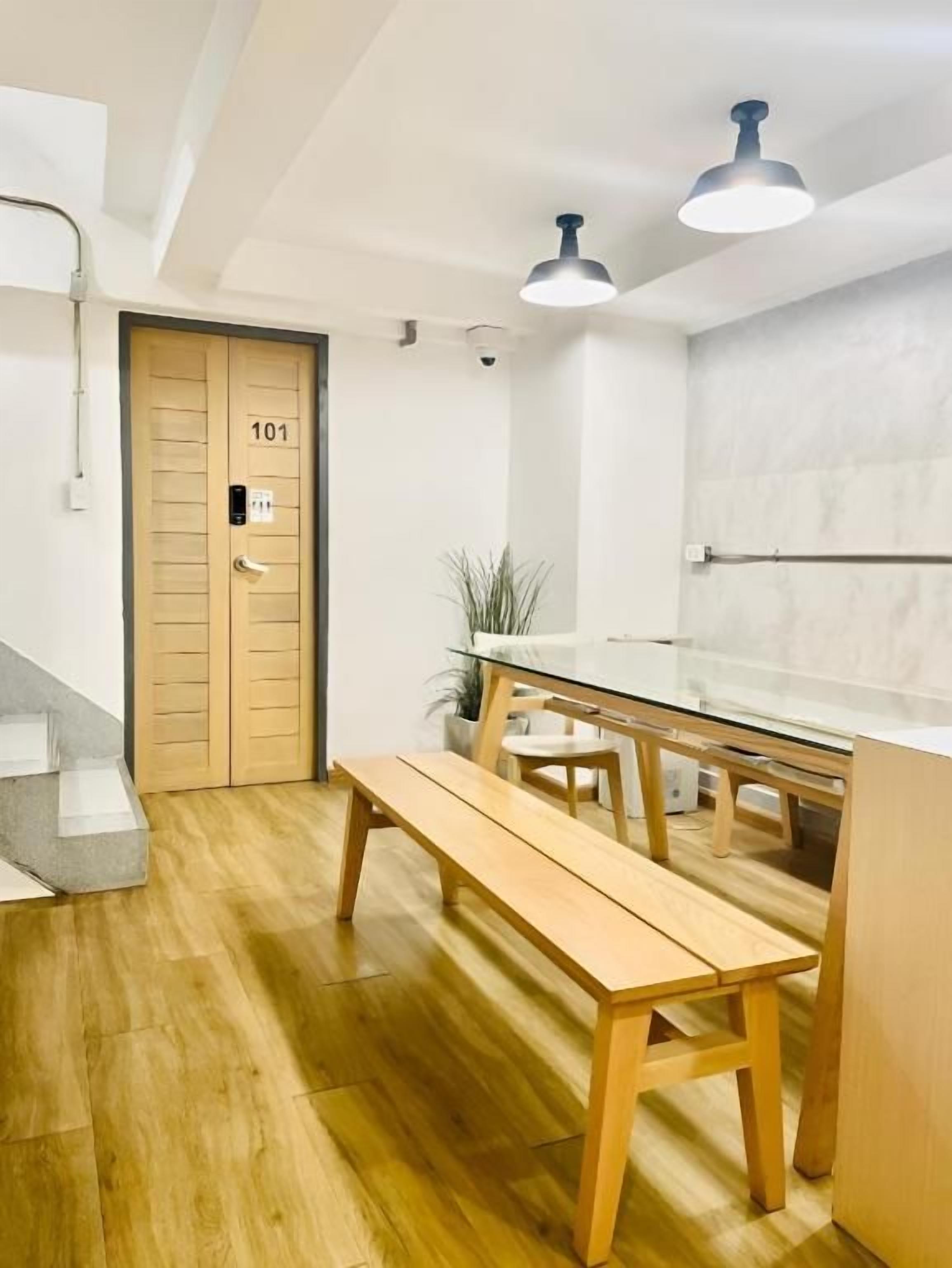 Un interior moderno con un banco de madera, una mesa de vidrio y una puerta con el número 101.