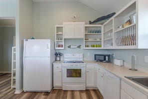 A kitchen with white cabinets, a refrigerator, a stove, a microwave, and a dishwasher. - 3 Block to Ocean! Walkable Crystal Beach Retreat (Bolivar Peninsula)