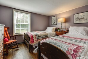A bedroom with two beds, a rocking chair, a dresser, and a window with blinds. - On 62-Acre Farm! Waterfront Home w/ Decks & Views (Meadows of Dan)