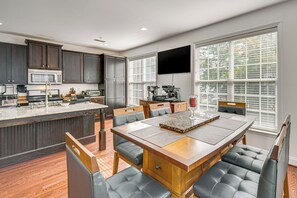 Een moderne keuken met donkerhouten kastjes, een centraal eiland en een eetgedeelte met een houten tafel en lederen stoelen.