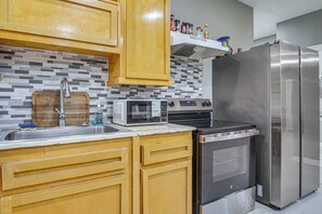 A kitchen with wooden cabinets, a stainless steel refrigerator, a microwave, and an oven. - San Benito Home w/ Pool, Close to Dtwn (San Benito)