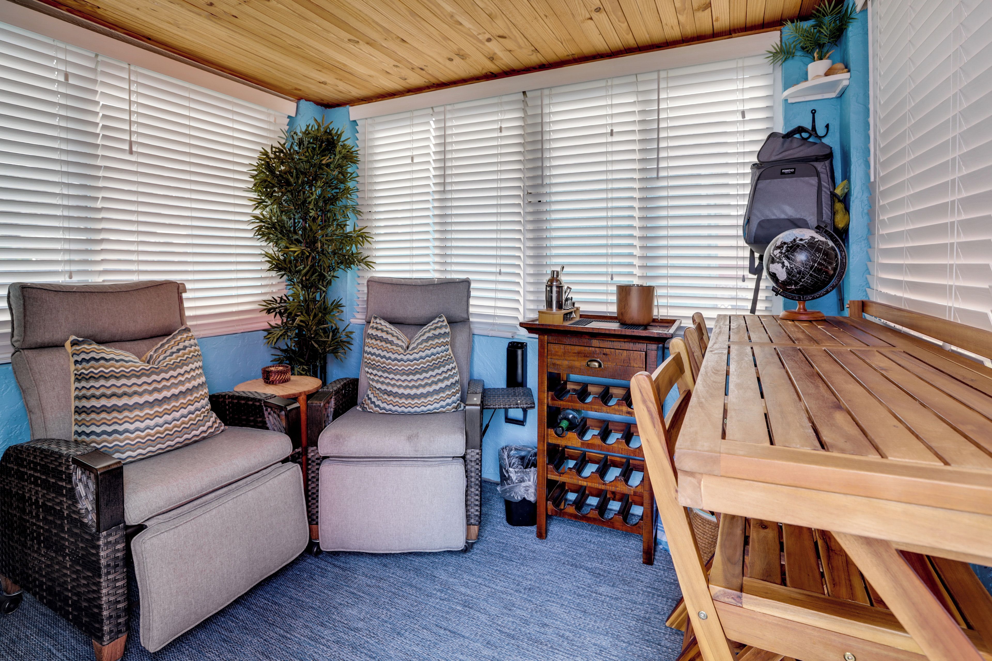 Een gezellige zithoek met een houten tafel, beklede stoelen en een wijnrek.