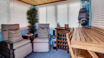 Een gezellige zithoek met een houten tafel, beklede stoelen en een wijnrek.