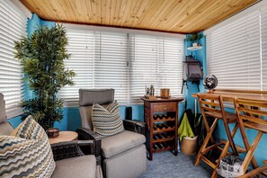 Une pièce chaleureuse avec un plafond en bois, un canapé agrémenté de coussins à motifs, une petite table et un meuble à bouteilles.