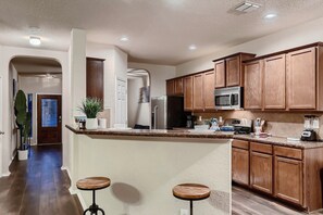 A kitchen with wooden cabinets, a microwave, a coffee maker, and a blender on the counter. - 7 Mi to SeaWorld! Group-Friendly Getaway w/ Pool (San Antonio)