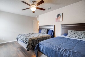 A bedroom with two beds, a ceiling fan, and a door leading to another room. - 7 Mi to SeaWorld! Group-Friendly Getaway w/ Pool (San Antonio)