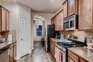 A kitchen with wooden cabinets, a stainless steel microwave, a black refrigerator, a stove, and a dishwasher. - 7 Mi to SeaWorld! Group-Friendly Getaway w/ Pool (San Antonio)