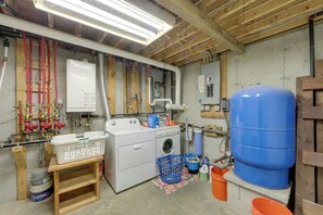 A laundry room with a washing machine, dryer, and various cleaning supplies. - Dock & River Access: Custom-Built Cabin in Oneonta (Oneonta)