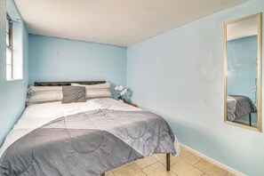 Ein Schlafzimmer mit einem Bett, einem Nachttisch, einem Spiegel und einem Fenster.