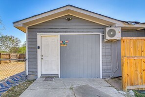 A small building with a white door, a welcome sign, and an air conditioning unit.