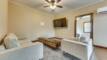 A living room with two sofas, a coffee table, and a ceiling fan.