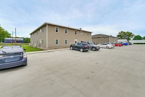 A parking lot with multiple vehicles, a building with a flat roof, and a clear sky.