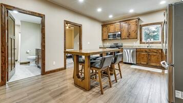 A kitchen with wooden cabinets, a stainless steel refrigerator, a microwave, and a sink.