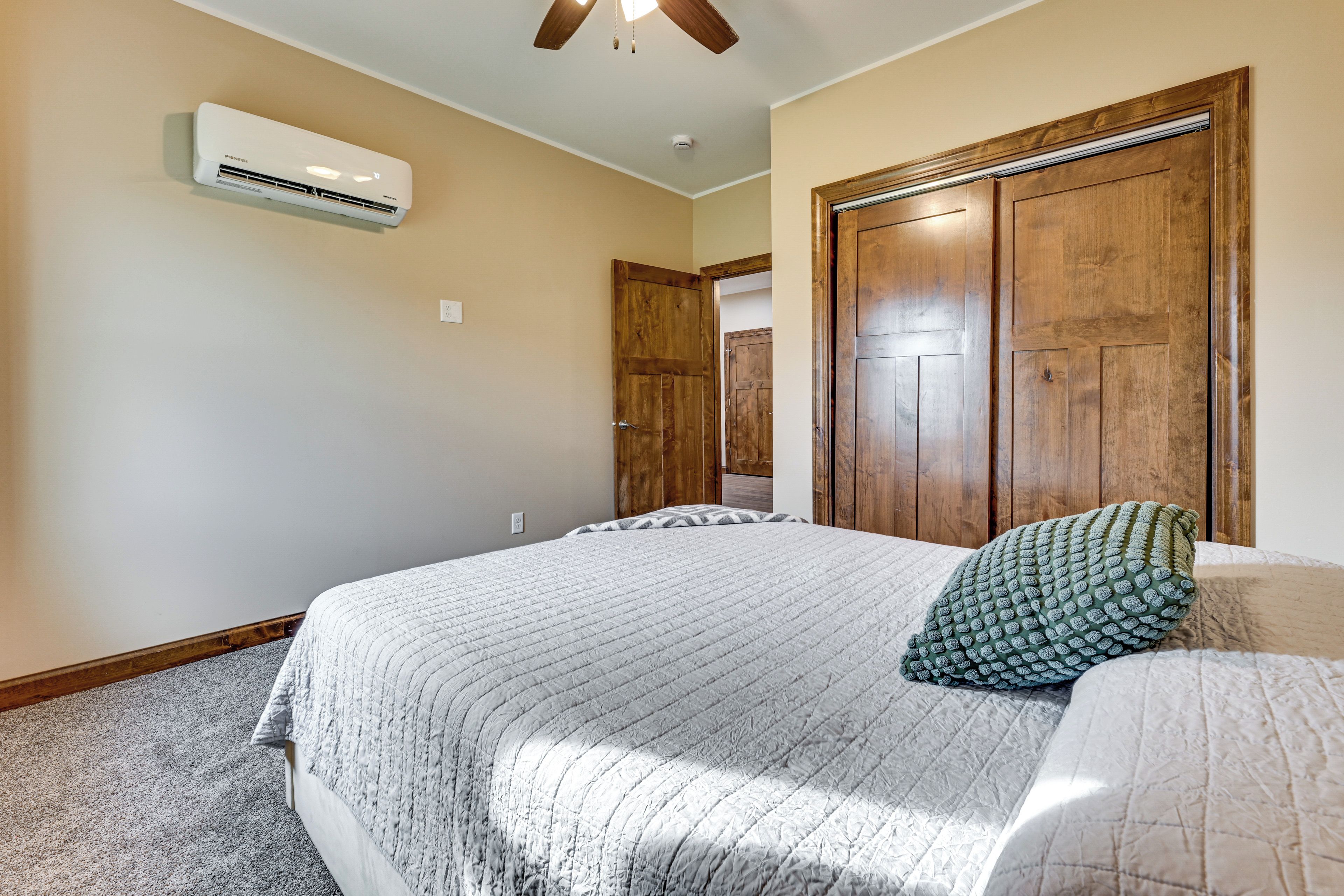 Un dormitorio con una cama, ventilador de techo, aire acondicionado y puertas de madera.
