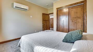 Un dormitorio con una cama, ventilador de techo, aire acondicionado y puertas de madera.
