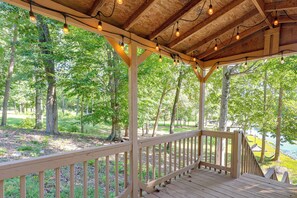 A wooden deck with a railing overlooking a forested area. - Gaston Lake House: Dock, Deck, Game Room! (Bracey)