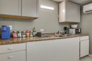 A kitchen with white cabinets, a granite countertop, a coffee maker, a microwave, and a dish rack. - Central Rio Grande Valley Hub w/ Full Kitchen! (La Feria)