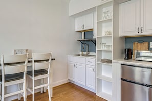 Eine moderne Küche mit weißen Schränken, einem Edelstahlkühlschrank und einer Holz-Schneidebrett.