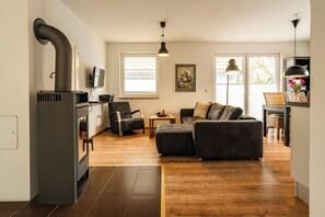Ett modernt vardagsrum med en soffa, en matplats och ett kök med en spis.