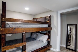 Ein Stockbett mit Holzrahmen und grauer Bettwäsche.
