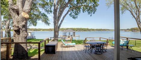 A wooden deck with outdoor furniture overlooking a lake.