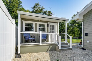 A covered porch with a set of stairs leading to a door, a small seating area with chairs, and a mailbox on the side. - *New To Market* | Riverfront Pigeon Forge Retreat (Pigeon Forge)