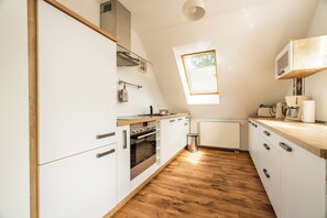 A kitchen with white cabinets, a wooden countertop, a built-in oven, and a window providing natural light. - Cozy vacation apartment with a sauna in Röbel on Lake Müritz (Röbel)