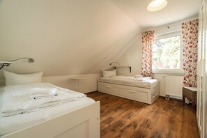 A bedroom with a bed, bedside table, and a window with curtains. - Cozy vacation apartment with a sauna in Röbel on Lake Müritz (Röbel)