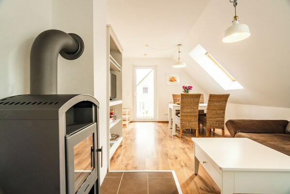 A modern kitchen with a built-in stove, a dining area with wicker chairs, and a loft bedroom with skylights. - Cozy vacation apartment with a sauna in Röbel on Lake Müritz (Röbel)