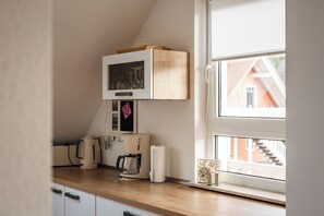 A kitchen with a wooden countertop, a microwave, a coffee maker, and a kettle. - Cozy vacation apartment with a sauna in Röbel on Lake Müritz (Röbel)