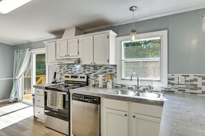 A modern kitchen with white cabinets, a stainless steel stove, and a large window. - 'Country Retreat' Near Wineries & Wedding Venues (Dobson)