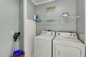 A laundry area with two front-loading washing machines, a drying rack, and a wall-mounted shelf with laundry supplies. - 'Country Retreat' Near Wineries & Wedding Venues (Dobson)