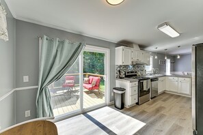 A modern kitchen with a sliding glass door leading to an outdoor deck, a built-in stove, and white cabinetry. - 'Country Retreat' Near Wineries & Wedding Venues (Dobson)