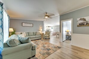 A living room with a sofa, a patterned rug, and a kitchen in the background. - 'Country Retreat' Near Wineries & Wedding Venues (Dobson)