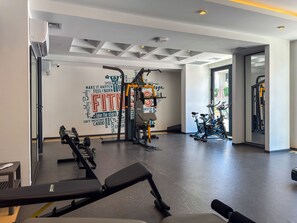 Un gimnasio con diverso equipo de ejercicio, una pared con mensajes motivacionales y vistas al exterior.