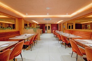 Un restaurante con mesasychairs y cabinas, suelo de baldosas y paneles de madera.