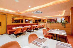A restaurant with booths and tables, wooden paneling, and potted plants.