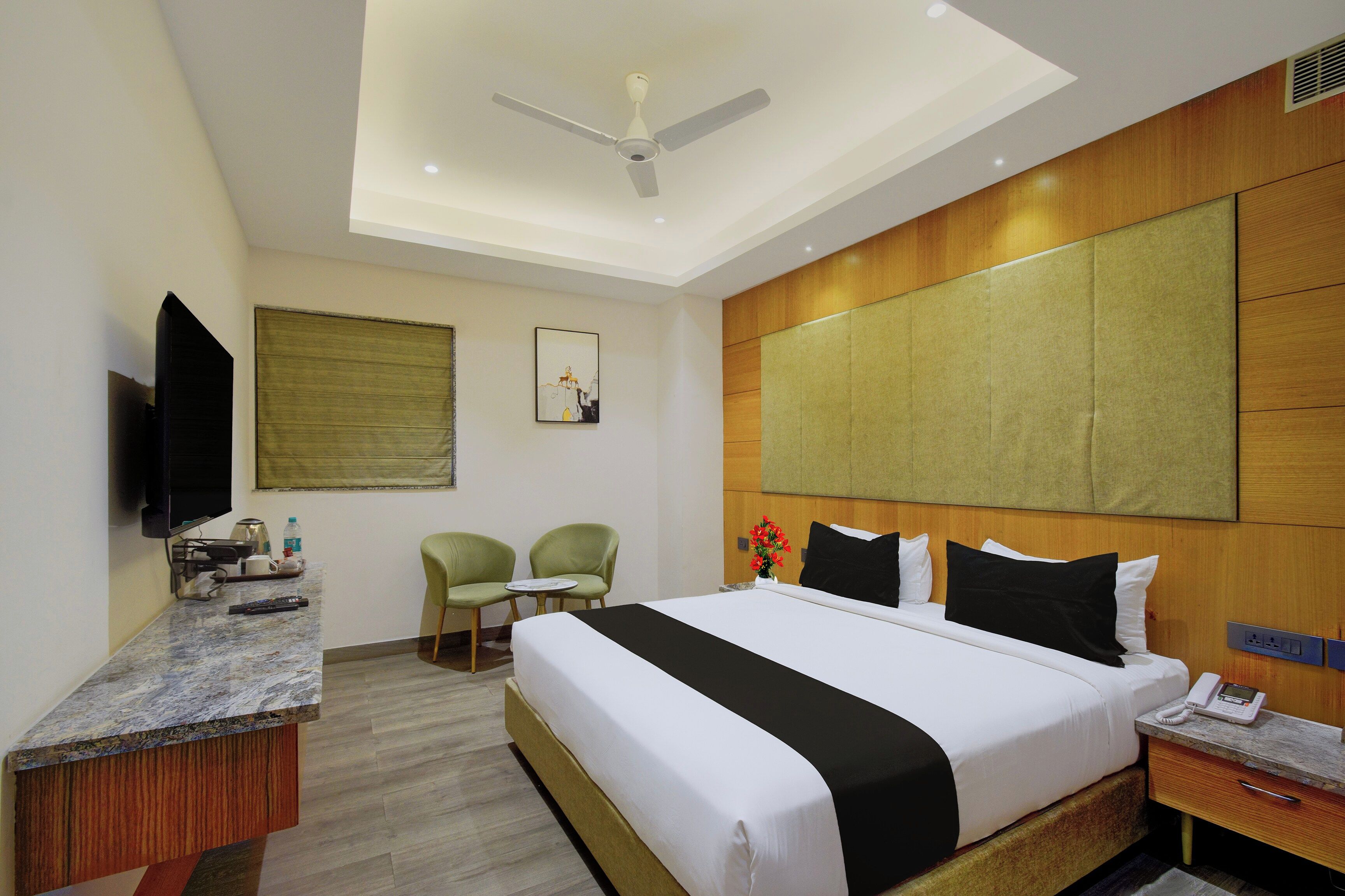 A hotel room with a bed, bedside table, TV, and a ceiling fan.