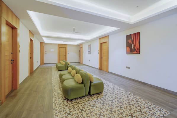 A hotel room with a long corridor, wooden doors, a ceiling fan, and a patterned rug.