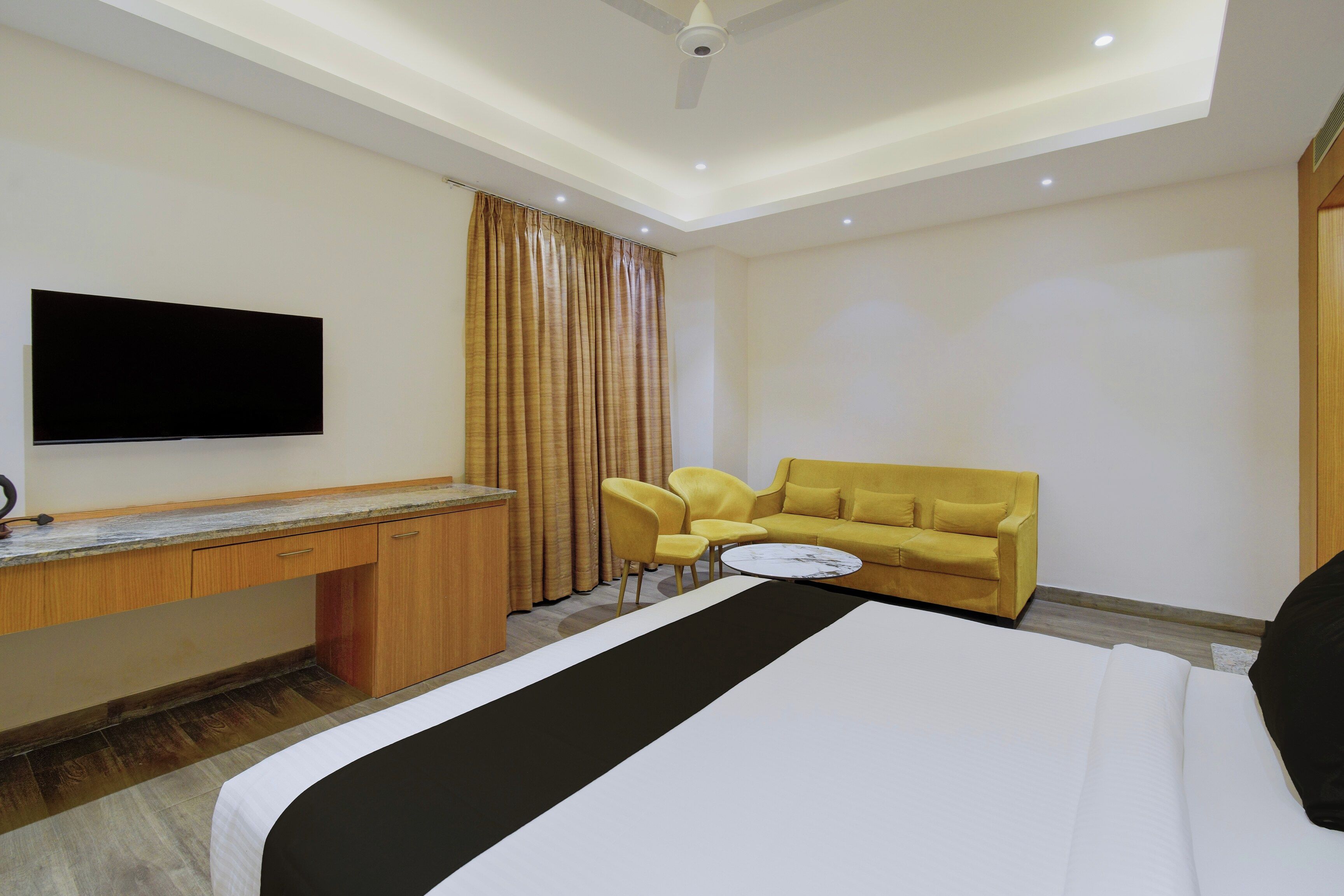 Ein Hotelzimmer mit Bett, Schreibtisch, Fernseher, Sofa und Sessel.