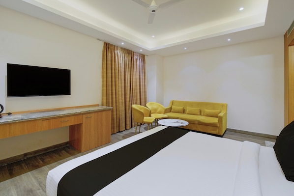 Una habitación de hotel con cama, escritorio, televisor, sofá y sillón.