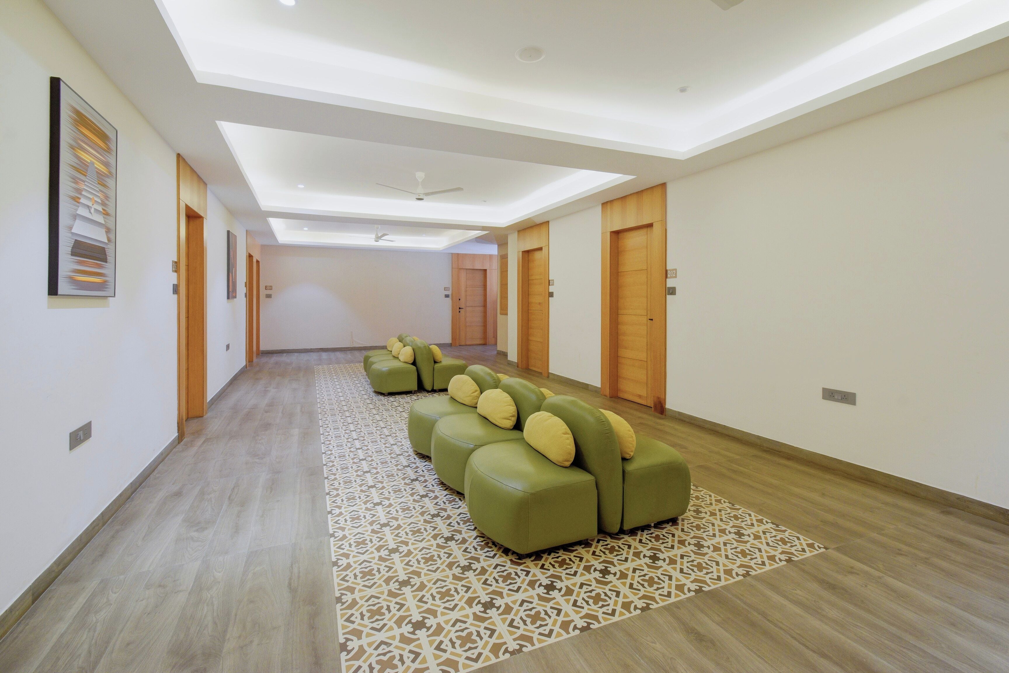 Corredor de hotel com área de estar, portas de madeira e um tapete estampado.