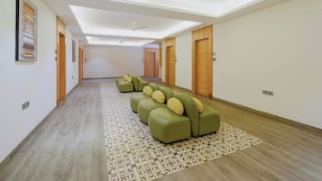 Corredor de hotel com área de estar, portas de madeira e um tapete estampado.