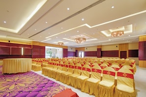 A conference room with rows of chairs, a patterned carpet, and a ceiling with recessed lighting and a chandelier.