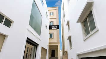 Un estrecho callejón entre dos edificios blancos, con un letrero que indica 'HOTEL' sobre la entrada.