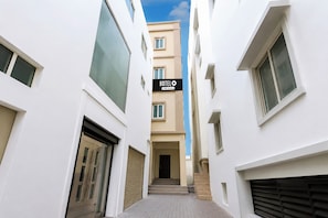 A narrow alleyway between two white buildings with a sign for 'HOTEL' above the entrance.